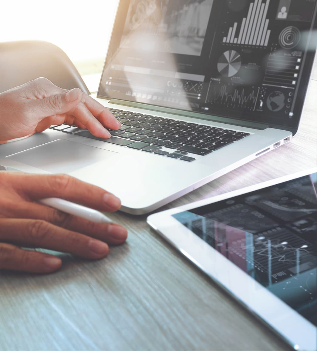 Hände eines Mannes tippen auf die Tastatur eines Laptops, auf dem Statistiken angezeigt werden