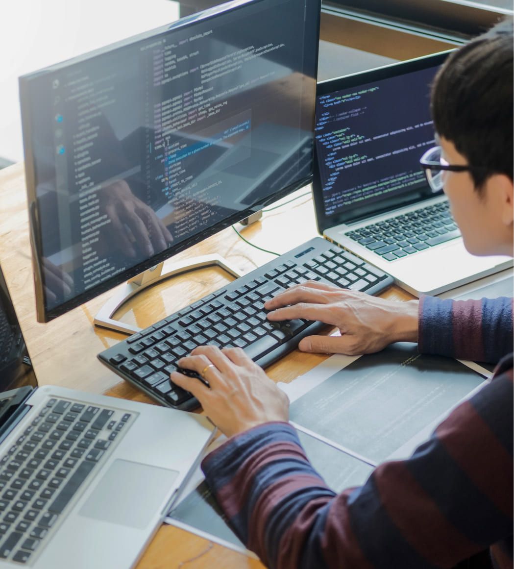 Junger Programmierer sitzt an einem PC und arbeitet an Code