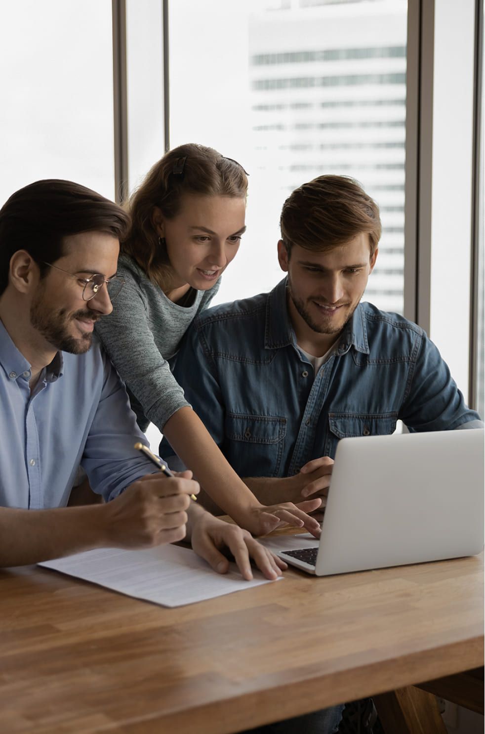 Gruppe von jungen Leuten, die zusammen auf einen Laptop schauen